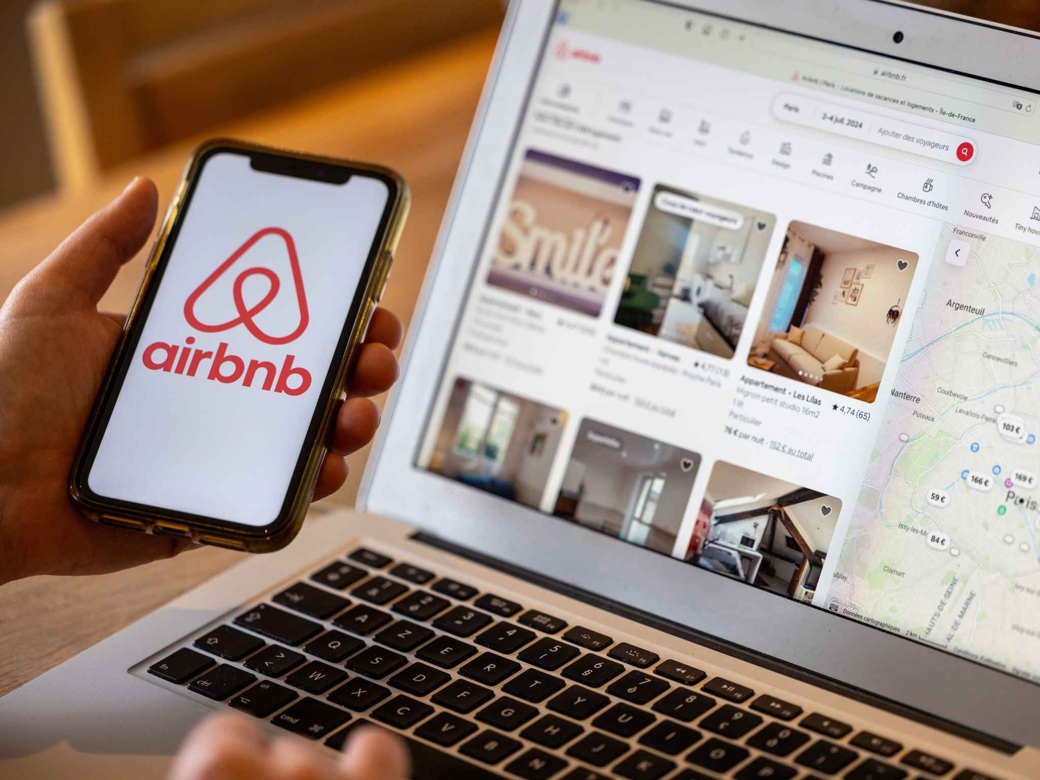 Person sucht auf Laptop und Smartphone nach AirBnB-Objekten