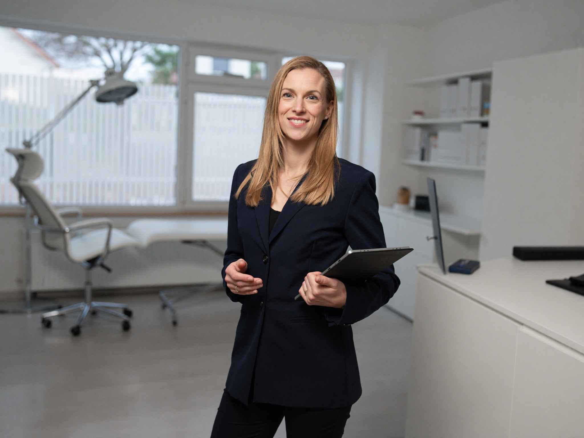 Katharina Heid mit Tablet in einer modern eingerichteten Arztpraxis.