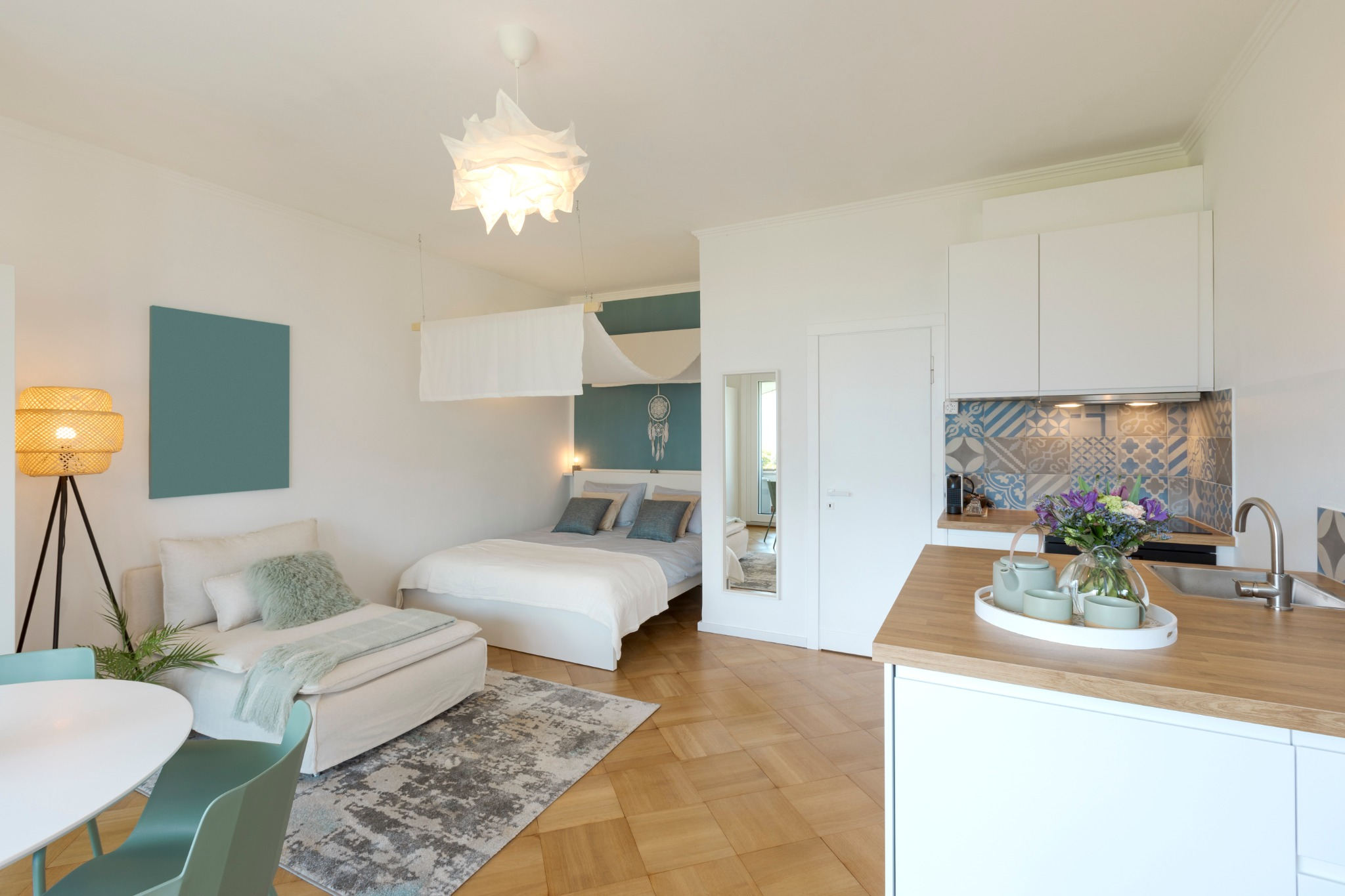 Helles, modern eingerichtetes Micro-Apartment mit Doppelbett, gemütlicher Sitzecke, Essbereich und offener Küche.